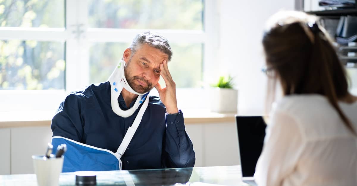 a man with an arm sling sits at desk - Coplan and Crane