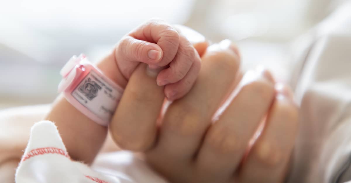 a newborn clutches a mother's finger | Coplan and Crane